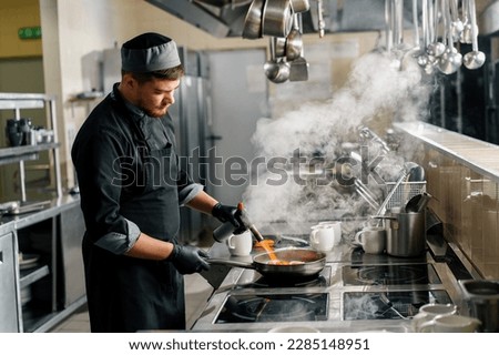 Professional kitchen in the hotel restaurant the chef is frying seafood on pan