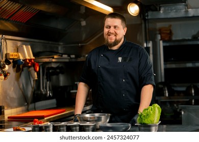 in professional kitchen portrait of a chef in a black jacket in the kitchen happy smile - Powered by Shutterstock