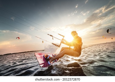 Professional Kite Surfer Woman Rides On A Board With A Plank In Her Hands On A Leman Lake With Sea Water At Sunset. Water Splashes And Sun Glare. Water Sports