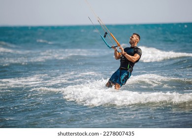 Professional kiter does the difficult trick. A male kiter rides against a beautiful background of waves and performs all sorts of maneuvers.