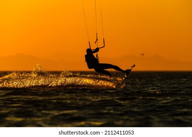 professional kiter jumping high against the setting sun - Shutterstock ID 2112411053