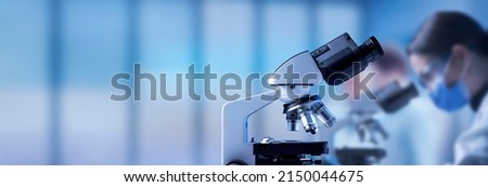 Professional laboratory microscope close up and scientists working in the background