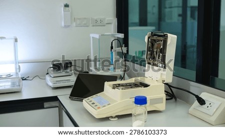 Professional laboratory workbench featuring a moisture analyzer, analytical balance, tablet, and glassware for quality control and scientific research.