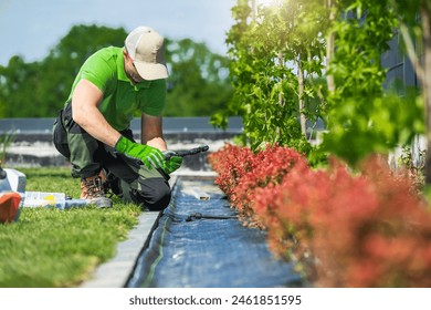 Professional Landscaper Installing Drip Irrigation System Inside a Garden - Powered by Shutterstock