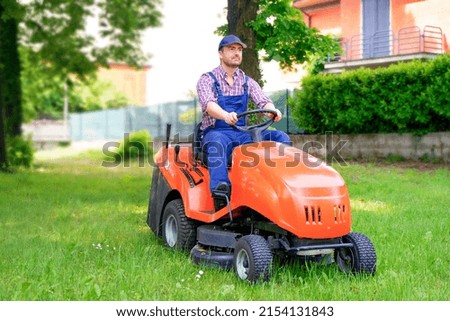 Professional lawn mower worker cutting grass in home garden