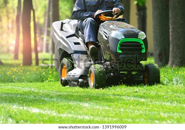 Professional lawn mower with worker cutting the
grass in a garden