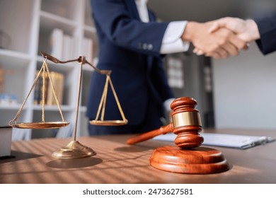 Professional Lawyer Handshake in Business Meeting with Scales of Justice and Gavel on Desk, Symbolizing Legal Agreement and Partnership in Modern Office Setting