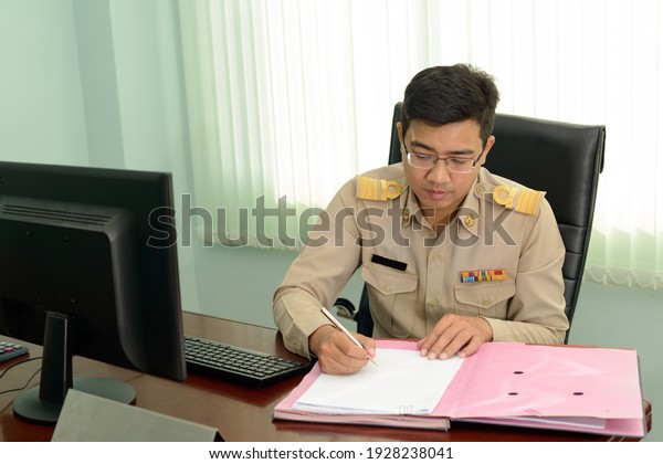 A Professional level Thai\
government officer, Civil servant signing the document on\
file.