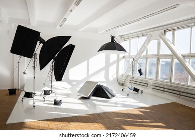 Professional lighting equipment, flashes, c-stands on a cyclorama in modern photo studio with a huge windows. Octabox, stripbox, softbox, buety plate and other stuff for photography.