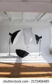 Professional lighting equipment, flashes, c-stands on a cyclorama in modern photo studio with a huge windows. Octabox, stripbox, softbox, buety plate and other stuff for photography.