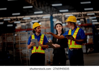 Professional logistics supervisor directing freight operations with diverse warehouse workers. Industrial staff wearing safety helmets planning safe cargo delivery.