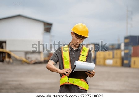 Professional logistics worker inspecting cargo containers at warehouse yard. Shipping, freight transport.