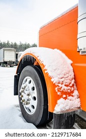 Professional Long Haul Classic Orange Big Rig Semi Truck Tractor With Extended Cab Standing Without Semi Trailer For Truck Driver Rest On The Winter Truck Stop Parking Lot Covered With Snow And Ice