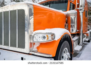 Professional Long Haul Classic Orange Big Rig Semi Truck Tractor With Extended Cab Standing Without Semi Trailer For Truck Driver Rest On The Winter Truck Stop Parking Lot Covered With Snow And Ice