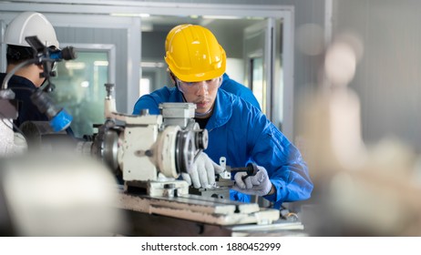 Professional Machinist And Foreman Engineer In Bear Suit Wearing Yellow Safety Helmet Focus On Operating Metal Lathe Grinding Machine For Handmade Work Piece At Factory. Industrial Working Concept.