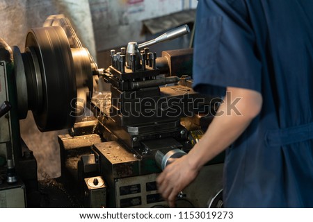 Professional machinist : man operating lathe grinding machine - metalworking industry concept.
Mechanical Engineering control lathe machine in factory.
