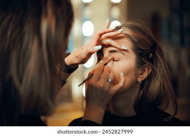 
Professional Make-up Artist Applying Eye-shadow with a Brush. Woman having her looks changed through professional makeup 
