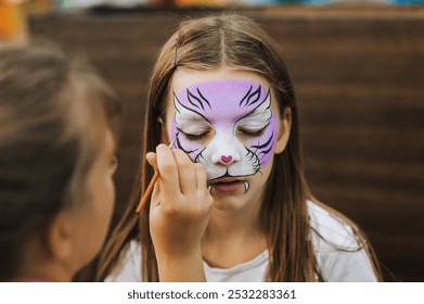 Professional make-up artist, female artist draws, does aqua make-up, make-up on a girl's face, a child's face with watercolors, a brush, a pencil at a holiday. Photography, portrait, creative concept. - Powered by Shutterstock