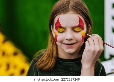 A professional make-up artist, artist paints with a brush on her face with multi-colored paints face painting, drawing, children's makeup for a little girl model. Portrait, art concept, lifestyle. - Powered by Shutterstock