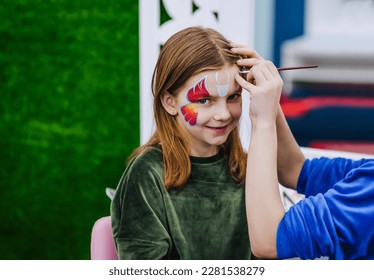 A professional make-up artist, artist woman paints on her face with paints face painting, drawing, children's makeup for a little beautiful girl, child. Photography, art, concept, lifestyle. - Powered by Shutterstock