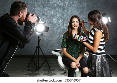 Professional makeup artist working with young beautiful woman at photo shooting - Powered by Shutterstock