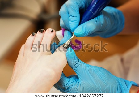 Professional making pedicure removing old coating in salon. Master chiropody shapes the nails. Female patient in the process of hardware pedicure procedure. Concept body care. Close up.