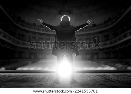 Professional male actor on the stage of the theater against the backdrop of an empty hall. Black and white photo