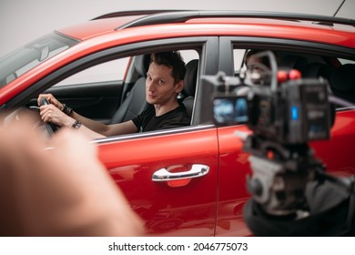 Professional male actor works in the frame on the set. Shooting with a car on a large white cyclorama. Handsome young man on the set of a movie, commercial or TV series. Filming indoors, studio