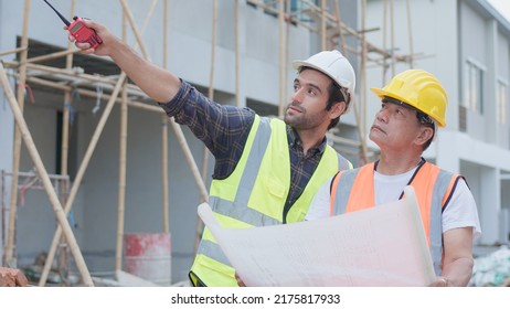 Professional Male Civil Engineer Or Architect, Inspector With Contractor, Foreman Or Worker. While Look At Blueprint Plan Inspect Discuss Meeting Building Project And Pointing On Construction Site.