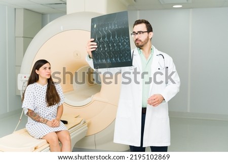 Professional male doctor looking at the MRI brain resonance of a young woman patient at the hospital