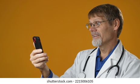 Professional Male Doctor Talking Looking At Phone Camera Making Conference Video Call. Physician Speaking To Web Cam Chatting With Patient Online Providing Remote E Health Medical Tele Health Concept 