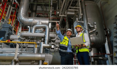 Professional male electrical engineer in safety uniform working and discussion at factory site control room. Industrial technician worker maintenance power system at manufacturing industry plant room. - Powered by Shutterstock