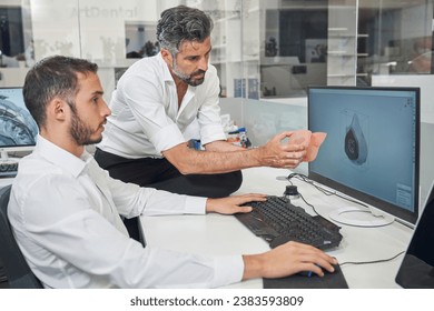 Professional male engineers observing respirator while designing 3d model of face mask on computer in model office during coronavirus epidemic - Powered by Shutterstock