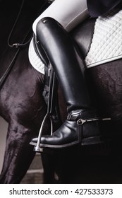 Professional male equestrian rider saddle up horse for dressage on training or competition - Unrecognizable closeup, focus on boots in stirrup. Concept of animal loving and having hobby