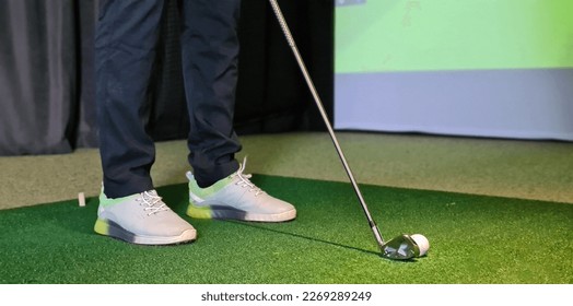 Professional male golfer playing golf indoors in golf simulator closeup. training field with screen - Shutterstock ID 2269289249