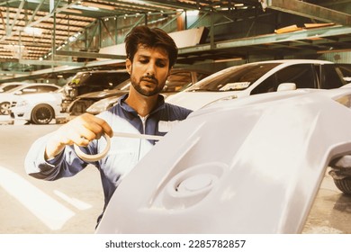 Professional male painters prepare for work use masking tape to cover the spray line not to mess up decorate the area that needs to be sprayed with a new primer : Car painting service in the garage. - Powered by Shutterstock