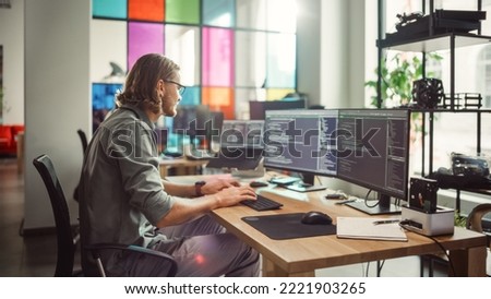 Professional Male Programmer Writing Code on Desktop Computer With Multiple Displays in Stylish Office. Caucasian Man Does Data Scraping For Artificial Intelligence Innovative Tech Start-Up.
