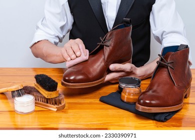 Professional Male Shoes Cleaner with Cleaning Brushes For Tan Derby Leather Boots While Working in Workshop With Rub Cloth. Horizontal Image - Powered by Shutterstock