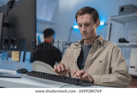 Professional Male Software Developer, Computer Programmer Concentrated on Software Development, Coding Application, Analyzing Cyber Security Code and Programming Task Sitting at Desk with Computer.
