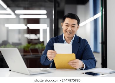 Professional male in a suit with a beaming smile holding an envelope, concept of good news or promotion at work. - Powered by Shutterstock