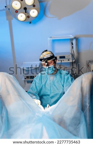 Professional male surgeon proctologist performing operation using special medical devices in the operating room in hospital. Urgent surgical concept