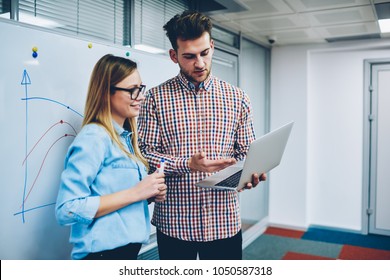 Professional male tutor showing presentation to successful student on laptop computer via internet connection.Female teacher and hipster guy discussing online video watched on website of netbook