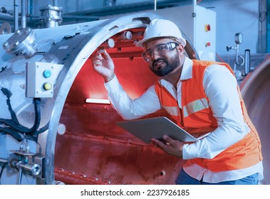 Professional male worker in hard hat works using the laptop to inspect and maintain machinery equipment in basil seed beverage factory. Concept. Beverage industry. Worker. Expert. - Powered by Shutterstock