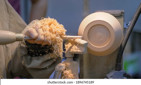 Professional Man Carpenter Using Skew Chisel For Shaping Piece Of Wood On Wood Turning Lathe At Workshop - Close Up Side View. Design, Carpentry, Craftsmanship, Manufacturing Concept