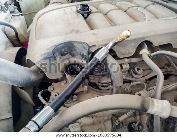 a professional man is changing the\
engine oil of a car and wearing white hand gloves \
