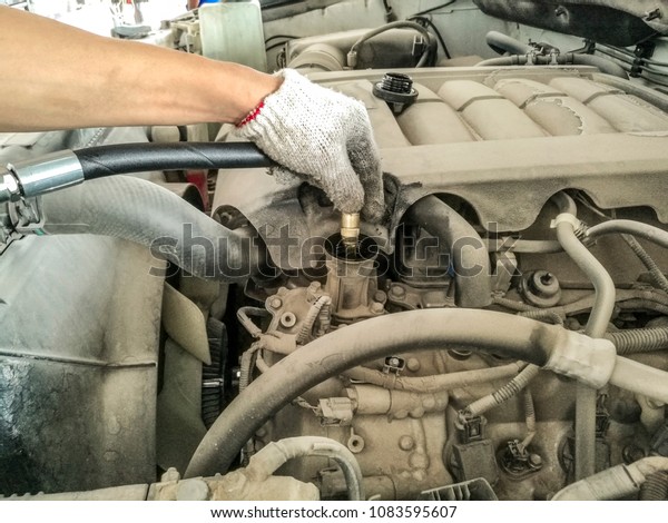 a professional man is changing the\
engine oil of a car and wearing white hand gloves \
