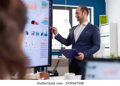 Professional man entrepreneur planning new project with his coworkers, explaning company strategy. Multiethnical businesspeople working in professional startup financial office during conference - Shutterstock ID 1939647508