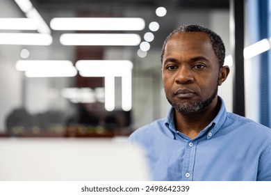 Professional man focused on task working on laptop in modern office setting. Intense expression showing concentration and dedication. Bright office lighting. Technology and productivity concepts. - Powered by Shutterstock