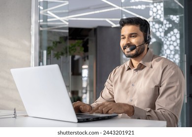 A professional man with a headset using a laptop in a modern office setting, conveying customer service and technology. - Powered by Shutterstock