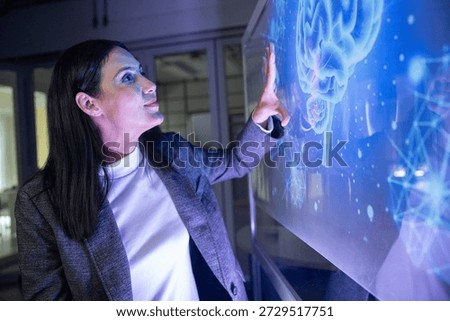 A professional man interacts with a high-tech circular data interface on a large digital screen, featuring graphs and data elements in a glowing blue theme.